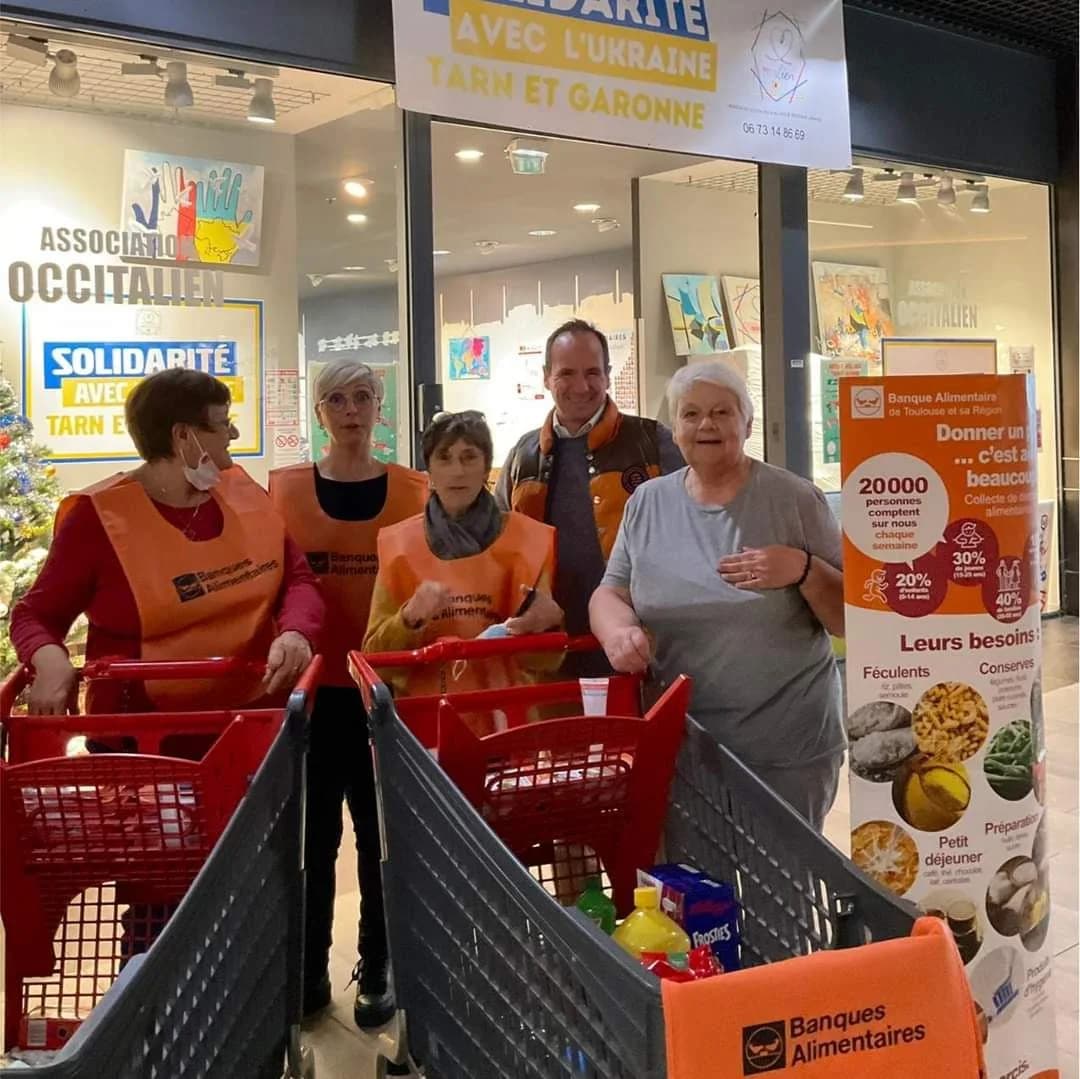 Des bénévoles en chasuble devant la devanture du local Occitalien, avec des caddies de la Banque Alimentaire.